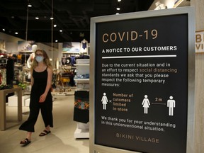 A "Covid-19" sign stands at the entrance of a retail store in Ottawa,  on Friday, June 12, 2020.