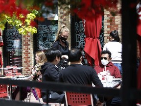 A customer wearing a protective mask sits outside at a restaurant in Ottawa.