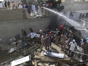 Soldiers and volunteers collect dead bodies at the site of a crash in Karachi, Pakistan, Friday, May 22, 2020.