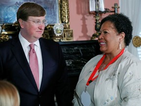 Mississippi Gov. Tate Reeves, left, speaks with Reena Evers, daughter of the slain civil rights activist Medgar Evers and Myrlie Evers-Williams, after signing a bill to retire the last state flag in the United States with the Confederate battle emblem, during a ceremony in Jackson, Miss., on Tuesday.