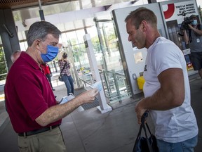 Mayor Jim Watson hands out masks at Tunney's Pasture LRT Station last month.