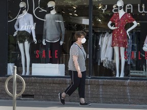 A woman wearing a mask walks past a Toronto retail clothing store with mannequins in masks during the Covid 19 pandemic. Small businesses have been struggling, and many will not be able to reopen.