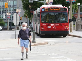 A man crosses the street near an OC Transpo bus.