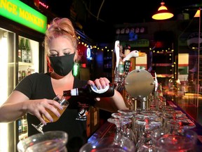 Bartender Tasha Holt pours a beer while wearing her mask at the Orange Monkey bar and billiards in Ottawa.