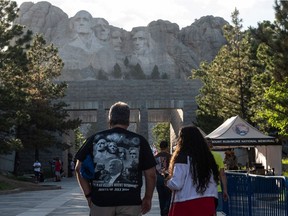 TOPSHOT - Visitors walk to see the Mount Rushmore National Monument  in Keystone, South Dakota on July 2, 2020. - US President Donald Trump is to visit the monument on July 3 and watch the first fireworks display at the monument in nearly a decade.