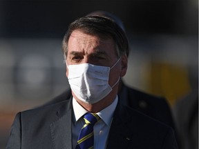 (FILES) In this file photo taken on May 12, 2020, Brazilian President Jair Bolsonaro wears a face mask as he arrives at the flag-raising ceremony before a ministerial meeting at the Alvorada Palace in Brasilia, Brazil, amid the new coronavirus pandemic. - As the number of dead from coronavirus shot up in Brazil, the popularity of far right President Jair Bolosonaro has remained unchanged.