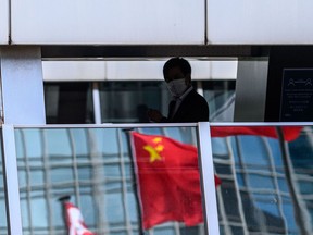 A man walks past a reflection of the Chinese flag on a footbridge in the Central district of Hong Kong on July 16.