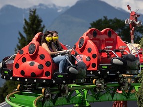 People wearing face masks ride an attraction at Playland amusement park at the Pacific National Exhibition, in Vancouver, on July 10.