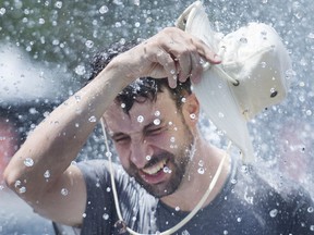 A man cools down under a water fountain.