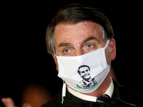 FILE PHOTO: Brazil's President Jair Bolsonaro speaks with journalists while wearing a protective face mask as he arrives at Alvorada Palace, amid the coronavirus disease (COVID-19) outbreak, in Brasilia, Brazil, May 22, 2020.