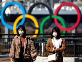 FILE PHOTO: People wearing protective face masks are seen in front of the Giant Olympic rings at the waterfront area at Odaiba Marine Park in Tokyo, Japan.