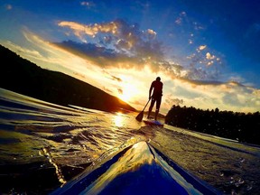 Stand up paddle boarders make their way towards the setting sun at Meech Lake.