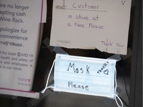 "Mask Please" is written on a protective mask hanging at a store in Ottawa on Friday, July 17, 2020.
