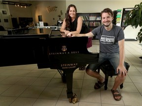 Jennifer Messer, manager of the Steinway Piano Gallery, and pianist Carson Becke pose with the nine-foot Steinway grand piano on Thursday. The store is starting outdoor "drive-in" concerts with it, and Becke will be performing outside the store twice on Monday morning, weather permitting.