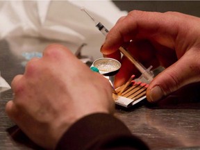 A man prepares heroin he bought on the street to be injected at the Insite safe injection clinic in Vancouver, B.C.,
