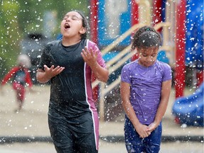 While Sofiya Ammar, 9 (right), seemed to just brave the chilly waters, her older sister, Mariam, 11,  drank in the cold water at the Barrhaven splash pad Monday — a welcome relief from the oppressive heat and humidity in the capital recently.