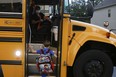 Paul Adamus, 7, climbs the stairs of a bus before the fist day of school on Monday, Aug. 3, 2020, in Dallas, Ga. Adamus is among tens of thousands of students in Georgia and across the nation who were set to resume in-person school Monday for the first time since March.