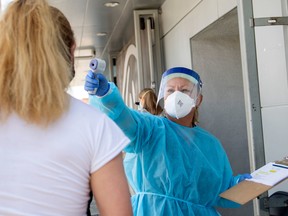 A health worker takes a patient's temperature before sending them to a tent to be tested.