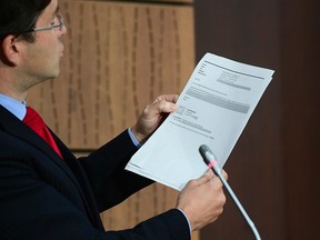 Conservative MP Pierre Poilievre holds up documents tabled by the Liberal government about the WE scandal, during a press conference on Parliament Hill on Aug. 19, 2020.
