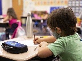 A student wears a protective mask during a lesson at an elementary school.