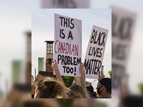 People hold signs during anti-racism protest in Brantford, Ont. on June 4
