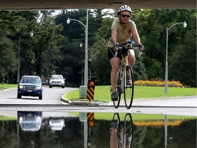 A  woman riding a bike past a puddle on Queen Elizabeth Drive in Ottawa