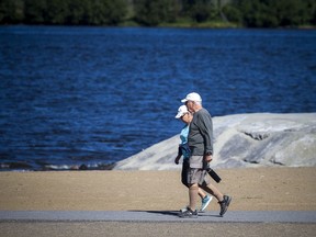 People walk on the trail along the beach at Petrie Island.
