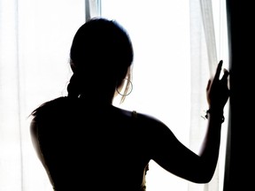 FILE: The silhouette of a woman looking outside.