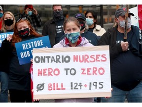Ottawa Hospital registered nurse Courtney Argue holds up her sign amidst about 40 to 50 other protesters.  Ottawa Hospital and social service workers held a protest Wednesday in front of local MPP Lisa MacLeod's office on Greenbank Road, but were eventually told by police to move from the strip mall property to a nearby sidewalk.