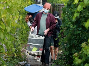 Housing worker Joshua Vannoppen (centre) helps tent city residents Dylan Moffatt, 26, right, and Raquel (no last name given), 28, move out their stuff before clean up of the area begins Thursday.