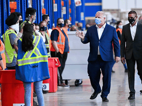 Ontario Premier Doug Ford waves to workers as he tours a warehouse where they ship personal protective equipment during the COVID-19 pandemic in Milton, Ont., on Sept. 30.