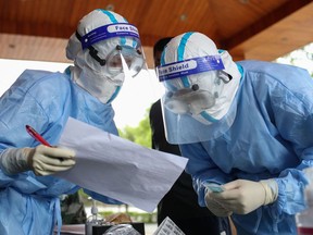 Medical workers check information as they prepare COVID-19 coronavirus testing.