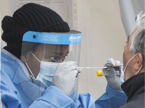 File photo/ A health-care worker prepares to swab a man at a walk-in COVID-19 test clinic in Montreal North, Sunday, May 10, 2020.