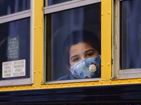 A student peers through the window of a school bus.