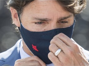 Prime Minister Justin Trudeau adjusts his face mask following a news conference where he paid a visit to the National Research Council of Canada (NRC) Royalmount Human Health Therapeutics Research Centre facility in Montreal, Monday, Aug 31, 2020.