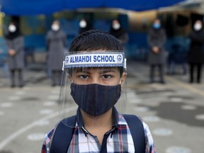 A student wearing a protective face mask and shield to help prevent the spread of the coronavirus disease (COVID-19), looks on as he poses for a picture at Al-Mahdi school in Tehran, Iran.