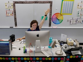 A teacher greets her first-grade students virtually from her classroom last week.