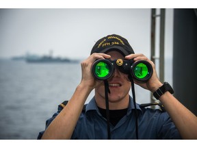 Able Seaman Kristian Sinclair uses his binoculars to spot flags on Korean Naval ships currently sailing with Her Majesty's Canadian Ship WINNIPEG, in this 2017 file photo.