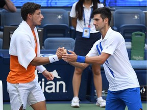 Novak Djokovic of Serbia shakes hands with Pablo Carreno Busta of Spain after being defaulted for striking a lines person with a ball on day seven of the 2020 U.S. Open tennis tournament at USTA Billie Jean King National Tennis Center.