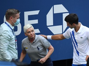 Novak Djokovic of Serbia and a tournament official tend to a linesperson who was struck with a ball by Djokovic during a match against Pablo Carreno Busta of Spain (not pictured) on day seven of the 2020 U.S. Open tennis tournament at USTA Billie Jean King National Tennis Center.