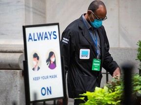 A trading official wearing a protective mask passes a mask required sign outside the New York Stock Exchange (NYSE) in New York, U.S., on Monday, Sept. 14, 2020.