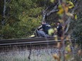 Cornwall Police Service investigators assess the scene where a body was found on Saturday along rail tracks in a wooded area.
