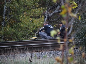 Cornwall Police Service investigators assess the scene where a body was found on Saturday along rail tracks in a wooded area.