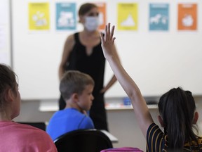 FILE: A pupil raises their hand in a classroom.