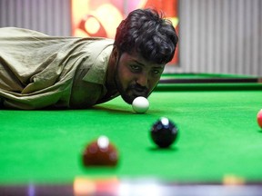 In this picture taken on September 28, 2020, Muhammad Ikram plays a shot with his chin at a local snooker club in Samundri. Ikram, who was born without arms, steps up to a snooker table, sizes up his options and with a firm flick of his chin strikes the cue ball and slots a red into a corner pocket.