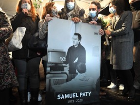 Relatives and colleagues hold a picture of Samuel Paty during the 'Marche Blanche' in Conflans-Sainte-Honorine, northwest of Paris, on Oct. 20, 2020, after the teacher was beheaded for showing pupils cartoons of the Prophet Mohammed.