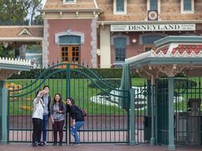 A file photo from March 14 shows people standing outside the gates of Disneyland Park in Anaheim.