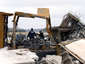 RCMP officers investigate the remains of a lobster pound that was destroyed by a fire, in Middle West Pubnico, N.S., October 17, 2020.