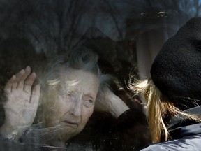 File photo/ A woman visits her 86-year-old mother through a window at the Orchard Villa long-term care home in Pickering.