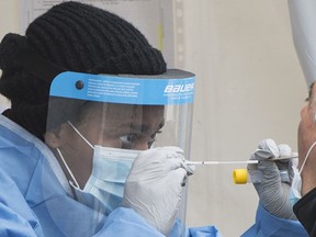 A health-care worker prepares to swab a man at a walk-in COVID-19 test clinic in Montreal North, Sunday, May 10, 2020.
